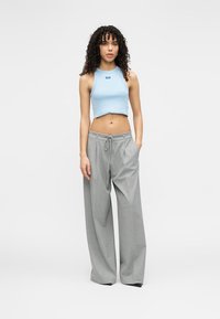 Ανοιχτό μπλε κοντό τοπ συνδυασμένο με φαρδιά γκρι παντελόνια με πιέτες μπροστά και ελαστική μέση με κορδόνι. Ομαλή υφή υφάσματος.