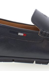 Mocassino in pelle blu navy con finitura texture. Presenta un accento cucito e un piccolo patch logo tricolore in rosso, bianco e blu.