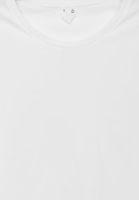 T-shirt en coton blanc avec un col rond, des manches courtes et une texture lisse. Dispose d'une étiquette d'entretien située au niveau du col.