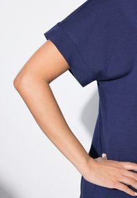 Mørkeblå kortærmet top lavet af blødt stof, med en afslappet pasform og rund halsudskæring, med en glat tekstur og enkelt design.