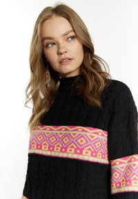 Pulover negru tricotat cu un model geometric colorat în roz, galben și albastru pe piept, cu guler înalt și finisaj texturat.