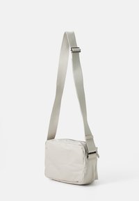 Rectangular shoulder bag in light beige, made of smooth, durable fabric. Features a wide adjustable strap and a zipper closure.