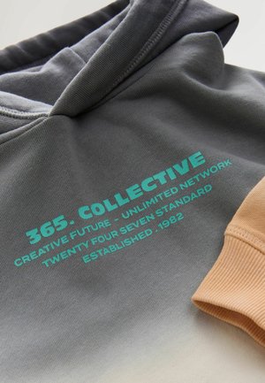 Kapuzenpullover mit einem Farbverlauf von Grau zu Creme, mit türkisfarbenem Text und einem orangen Akzent am Ärmel. Weiche Stofftextur.