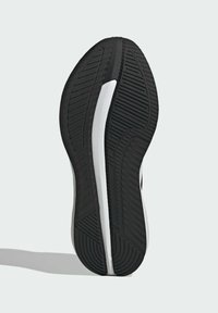 Czarna gumowa podeszwa buta z teksturowanym wzorem antypoślizgowym, zakrzywionym kształtem i białym paskiem biegnącym wzdłuż boku.