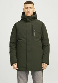 Mørkegrøn isoleret parka med en tætsiddende hætte, lynlås- brystlomme og kontrasterende sømdetaljer. Konstrueret af glat, vandafvisende materiale.