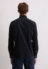 Schwarzes Langarmhemd mit glatter Textur, regulärem Kragen und Knopfmanschetten; verfügt über einen abgerundeten Saum und einfache Designelemente.