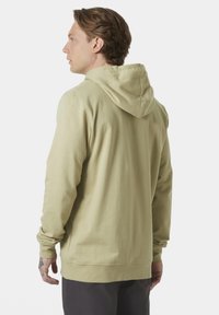 Sudadera con capucha de color verde claro, hecha de una tela suave, con mangas largas y un ajuste relajado. Puños y dobladillo acanalados, textura suave, diseño sencillo.