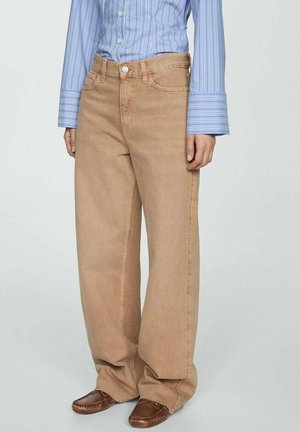 Beige wijde jeans van denim, met een knoopsluiting en zijzakken. Gede gedragen met een blauw-wit gestreept shirt en bruine schoenen.
