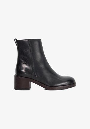 Bottine en cuir noir avec un bout rond, des détails de couture sur le côté et un talon bloc. Texture lisse et design minimaliste.