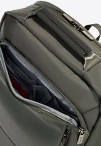 Sac à dos en tissu gris avec une surface texturée, plusieurs poches intérieures grises et rouges, et un tirette noir élégant.