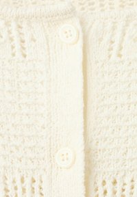 Cardigan en tricot couleur crème avec motif ajouré texturé et deux boutons ronds visibles à l'avant.