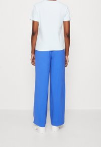 Camiseta corta de manga azul clara combinada con pantalones sueltos de un azul brillante. Los pantalones tienen una textura suave y un ajuste relajado.