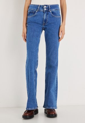 Vaqueros de mezclilla azul acampanados con una cinturilla alta, cinco bolsillos y cierre de doble botón. Textura lisa con detalles de costuras en los costados.