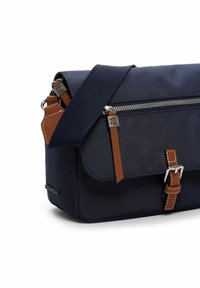 Dunkelblaue Umhängetasche mit braunen Leder-Zipperanhängern und Schnallenriemen, silberner Hardware und verstellbarem Schultergurt.