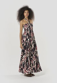 Vestido largo con cuello halter, con un estampado floral en rojo y crema sobre un fondo negro, confeccionado con tela ligera.