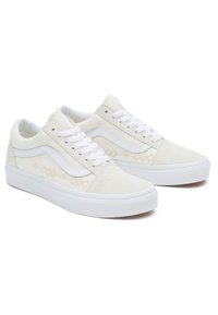 Krémové nízké tenisky s bílým bočním pruhom, jemnými vyšívanými geometrickými vzory, bílými tkaničkami a silnými bílými gumovými podrážkami.