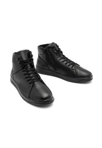 Czarne skórzane buty typu high-top mają gładką fakturę, sznurowane z przodu i z boku zapinane na zamek. Podeszwa jest płaska z delikatnym wygięciem.