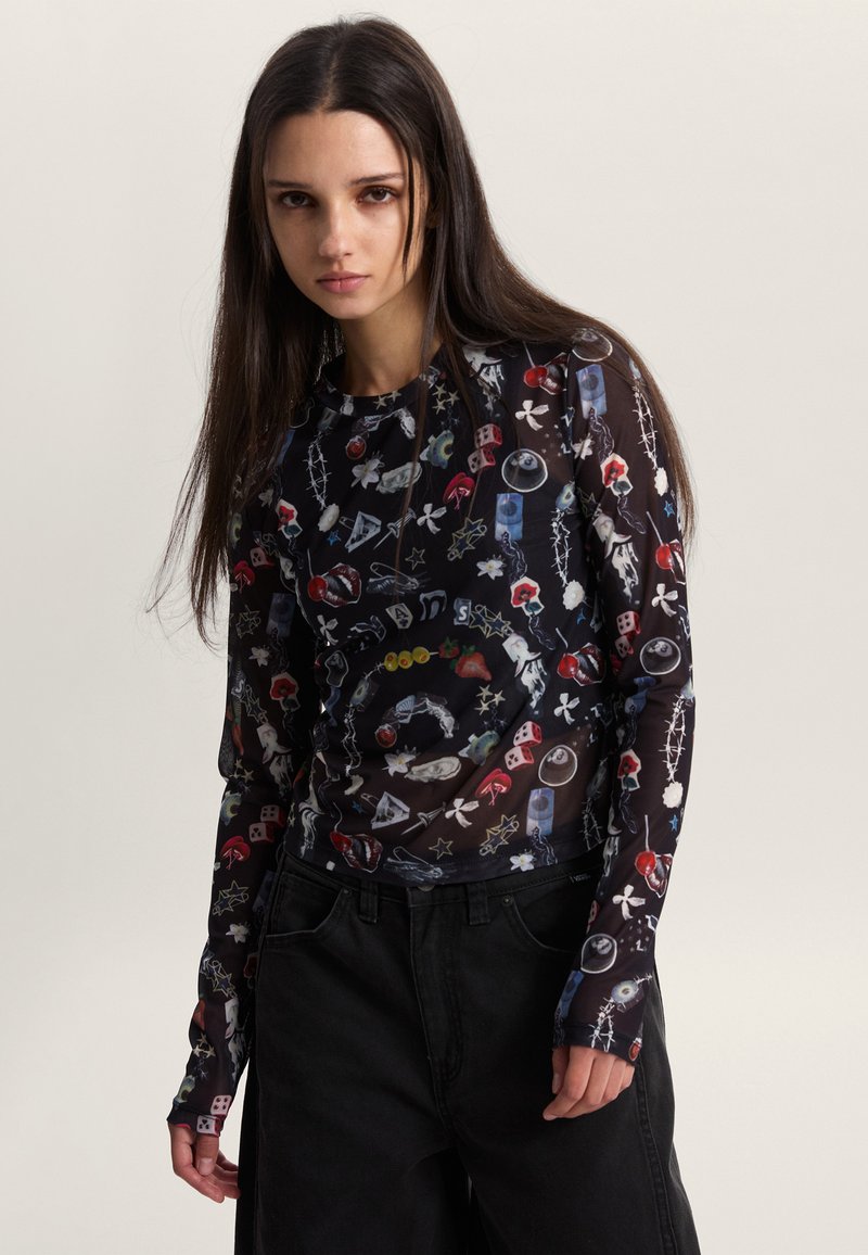 Haut transparent à manches longues noir avec des imprimés graphiques multicolores, comprenant des motifs tels que des fleurs, des icônes de jeu et des designs abstraits.