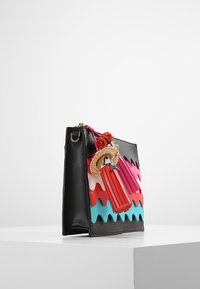 Sorth læderhåndtaske med farverige bølgemønstre i pink, rød og blå. Inkluderer en dekorativ tilbehør, der ligner en mini-paraply.