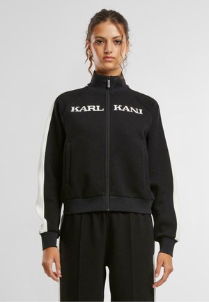 Svart zip-up sweatshirt med vita detaljer och "KARL KANI" broderat på bröstet, med sidofickor och ribbade ärmslut.