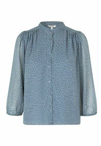 Blouse bleue à manches longues bouffantes, col mandarin, et pois blancs. Dotée d'une patte de boutonnage à l'avant et d'un tissu transparent.