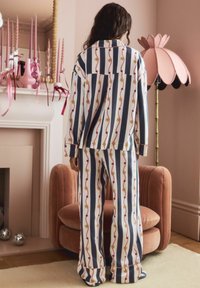 Gestreiftes Schlafanzug-Set in Blau, Weiß und Gold mit Blumenmustern. Weicher Stoff, weite Beine und lockerer Sitz.