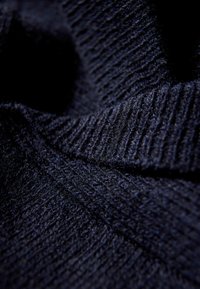 Ciemnogranatowa dzianina o żeberkowanej fakturze z różnorodnymi wzorami. Miękka, gęsta powierzchnia z subtelnymi różnicami odcieni.