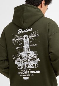 Σκούρο πράσινο φούτερ με λευκή γραφική εκτύπωση ενός φάρου, αλόγων και κειμένου. Το υλικό φαίνεται μαλακό; ο σχεδιασμός περιλαμβάνει κουκούλα με κορδόνι.