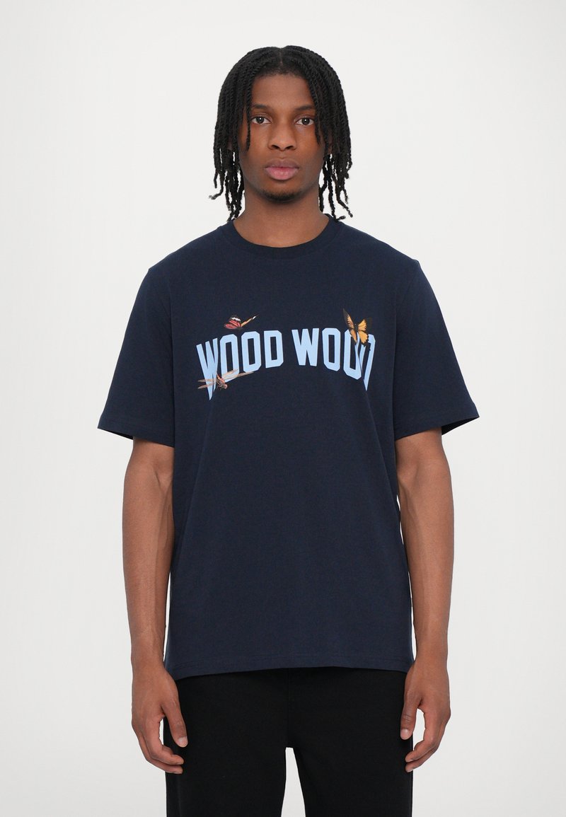 Camiseta de algodón azul marino con un logo curvado "WOOD WOOD" en azul claro, y pequeños gráficos de mariposa en el frente. Mangas cortas, ajuste relajado.
