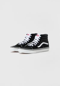 Czarne trampki typu high-top z białymi sznurowadłami, posiadające białą boczną paskę, czarną zamszową cholewkę i kontrastującą białą gumową podeszwę.