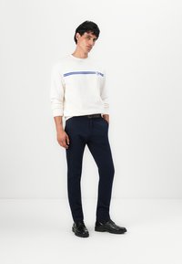 White sweatshirt with blue horizontal stripes, navy pants, and black leather shoes. Fitted design, smooth texture, and simple accents.