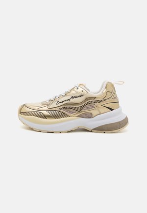 Beige og guld chunky sneakers med bølgende sorte linjemønstre, hvide snørebånd, tyk hvid sål og brandnavn indskrift på siden.