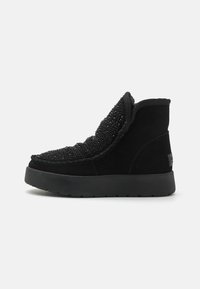 Botas altas negras de ante con detalle de cuentas texturizadas en la parte superior, que cuentan con una gruesa suela de goma negra y un cuello acolchado.