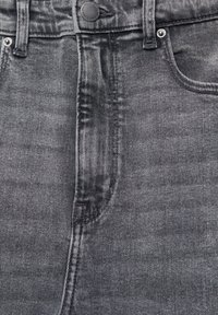 Czarne dżinsy z denimu z wysokim stanem, delikatnymi przetarciami, zapięciem na guziki i tradycyjnym układem kieszeni. Gładka faktura z widocznym przeszyciem.