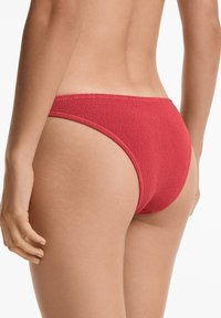 Slip bikini rosso con taglio a vita bassa e lati stretti, realizzato in tessuto lavorato a maglia per un aspetto e una sensazione uniche.