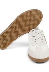 Zapatillas blancas con material de gamuza y cuero, que cuentan con una suela de goma texturizada, cierre con cordones y un detalle de diseño sutil en el lateral.