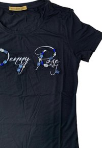 Maglietta nera con maniche corte e scollatura rotonda, decorata con un motivo testuale in pietre blu e trasparenti.