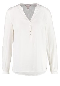 Blouse blanche à manches longues avec col en V, patte partielle à quatre boutons et coupe décontractée.