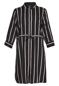 Abito camicia a righe nere con maniche lunghe, davanti con bottoni, due tasche sul petto e cintura legata in vita. I dettagli includono sottili righe beige.
