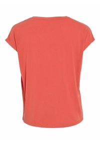 Camiseta de manga corta color coral con escote redondo, textura suave y un corte holgado; presenta aberturas laterales para mayor libertad de movimiento.
