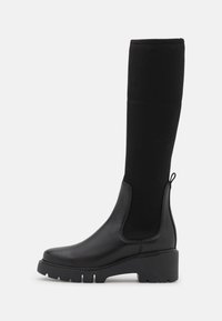 Bottines noires jusqu'au genou en cuir lisse avec un haut en tissu côtelé, un talon évasé et une semelle texturée pour une meilleure adhérence.