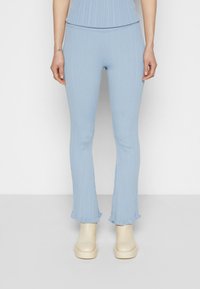 Leggings plissés bleu clair avec une texture côtelée et un ourlet volanté. Associés à des chaussures à plateforme lisses de couleur crème.