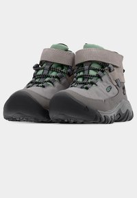 Γκρι ορειβατικά μποτάκια με πράσινες λεπτομέρειες, με λουράκι βέλκρο και μαύρα κορδόνια, υφασμένα ελαστικά πέλματα και ανθεκτικό σουέντ υλικό.