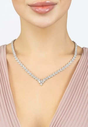 Silver necklace with a braided design, featuring sparkling round stones, V-shaped accent at the front, worn against a neutral background.