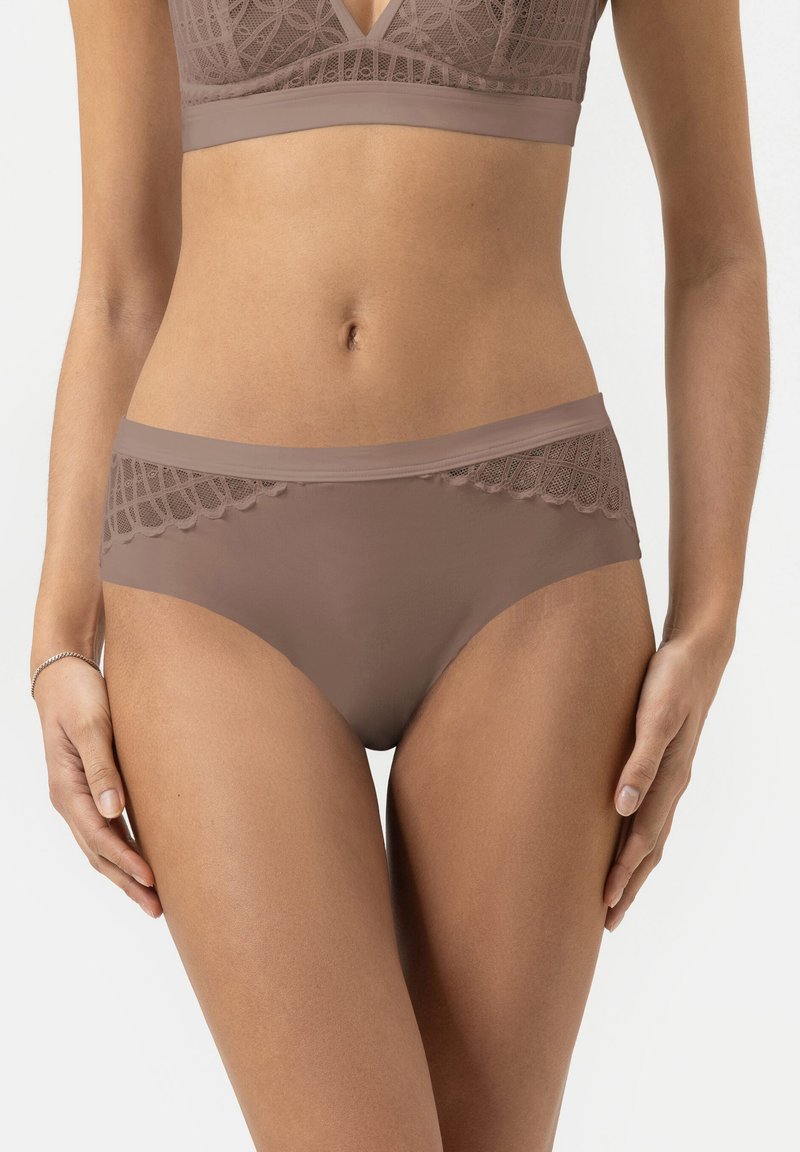 Brown seamless hipster underwear with lace detailing at the waistband, smooth texture, and a moderate rise, positioned on a model's hips.