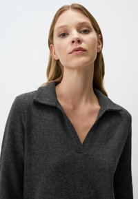 Dunkelgrauer Pullover mit Kragen-Ausschnitt, V-Ausschnitt vorne und weicher Textur, ausgestattet mit langen Ärmeln und lockerer Passform.