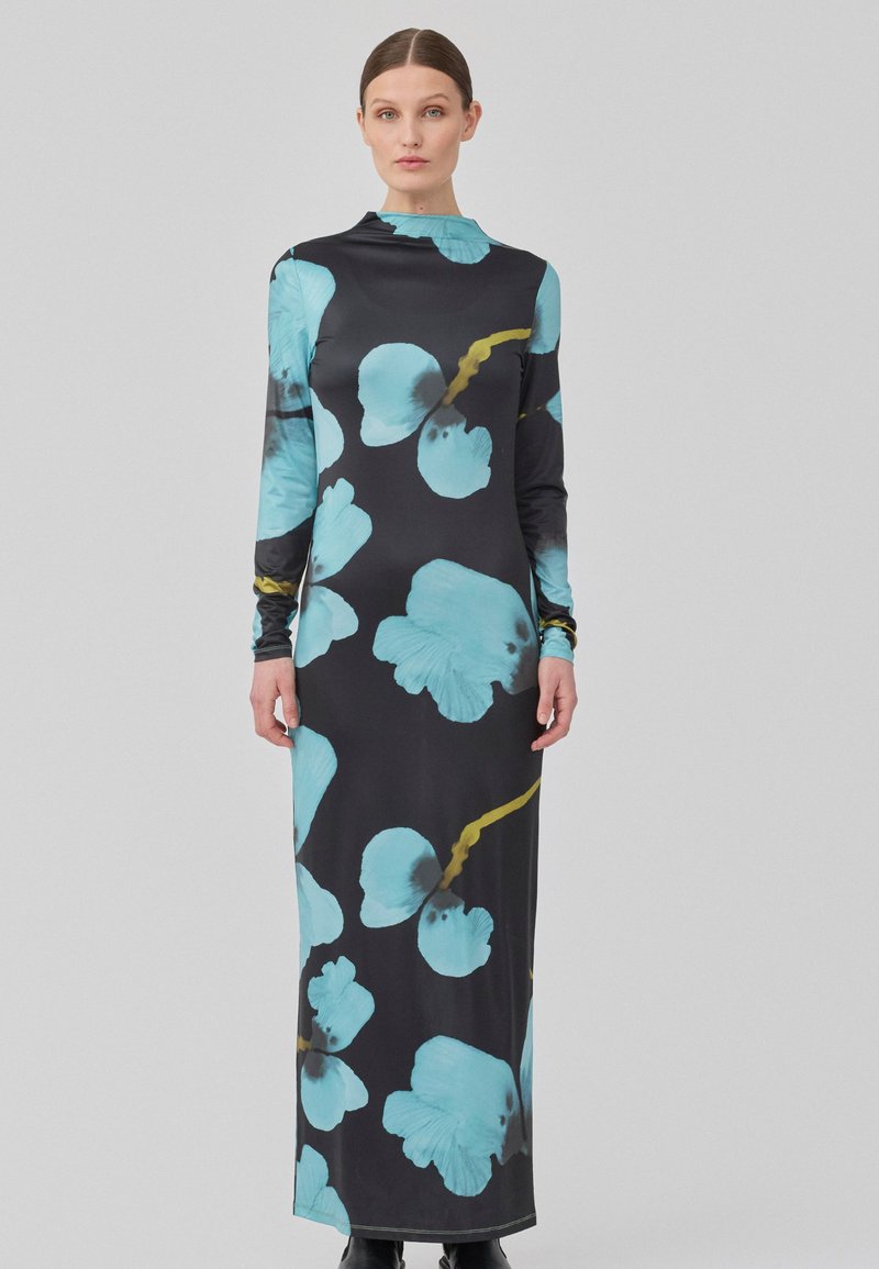 Robe noire à manches longues ornée de grands motifs floraux turquoise et d'accents jaunes, fabriquée en tissu extensible et lisse.