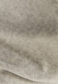 Grå, texturerad tyg med ett subtilt spräckligt mönster. Materialet verkar mjukt med en lätt lyster och visar en smidig, flödande form.