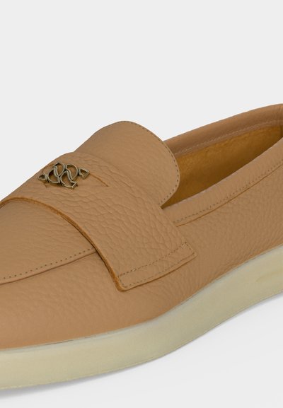 Pantof slip-on din piele texturată de culoare cămilă, cu talpă albă și mic detaliu decorativ metalic pe partea superioară.