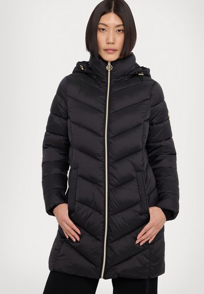 Manteau doudoune noir avec un design en chevrons, col montant, fermeture éclair et accents dorés. Comprend des poches latérales et une capuche.